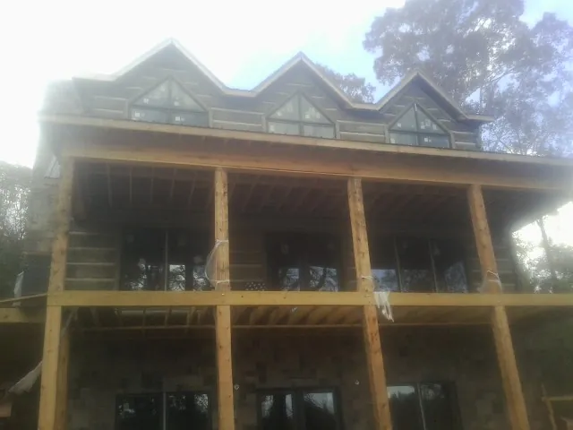 Dormers and porch framing on a large log home under construction — Roof Coating work by our crew in Waycross