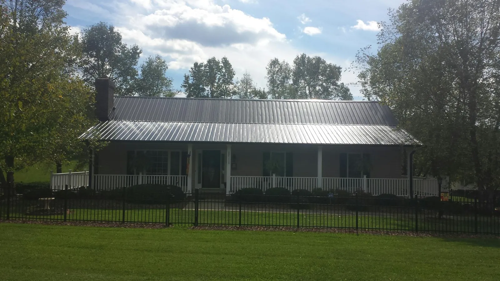 Gray metal roof on a brick ranch with a full width front porch — Gutter Guard Installation work by our crew in Waycross