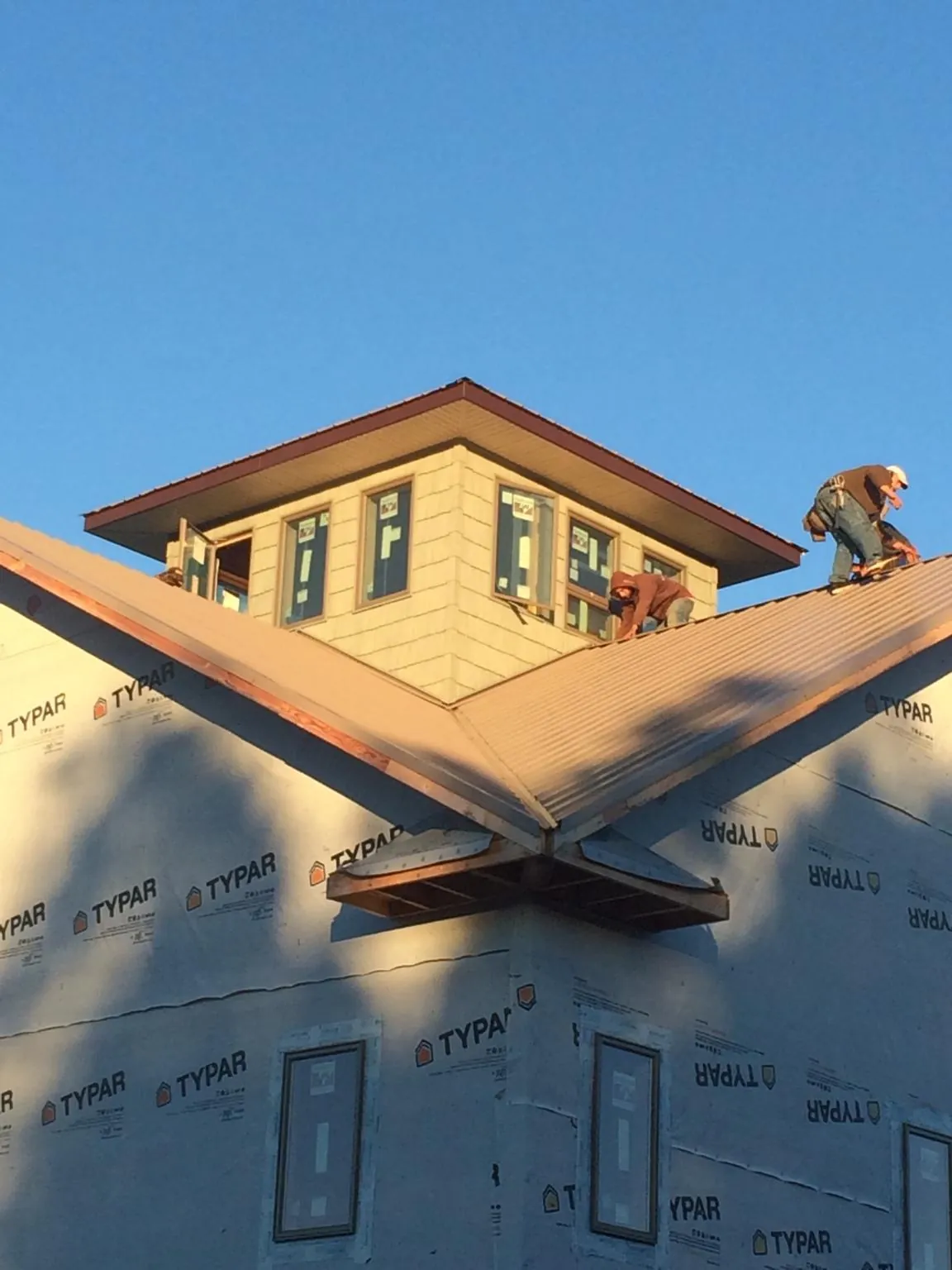 Roofers working around a rooftop cupola on a new metal roof at sunset — Roof Waterproofing in Waycross by Roofing Brothers